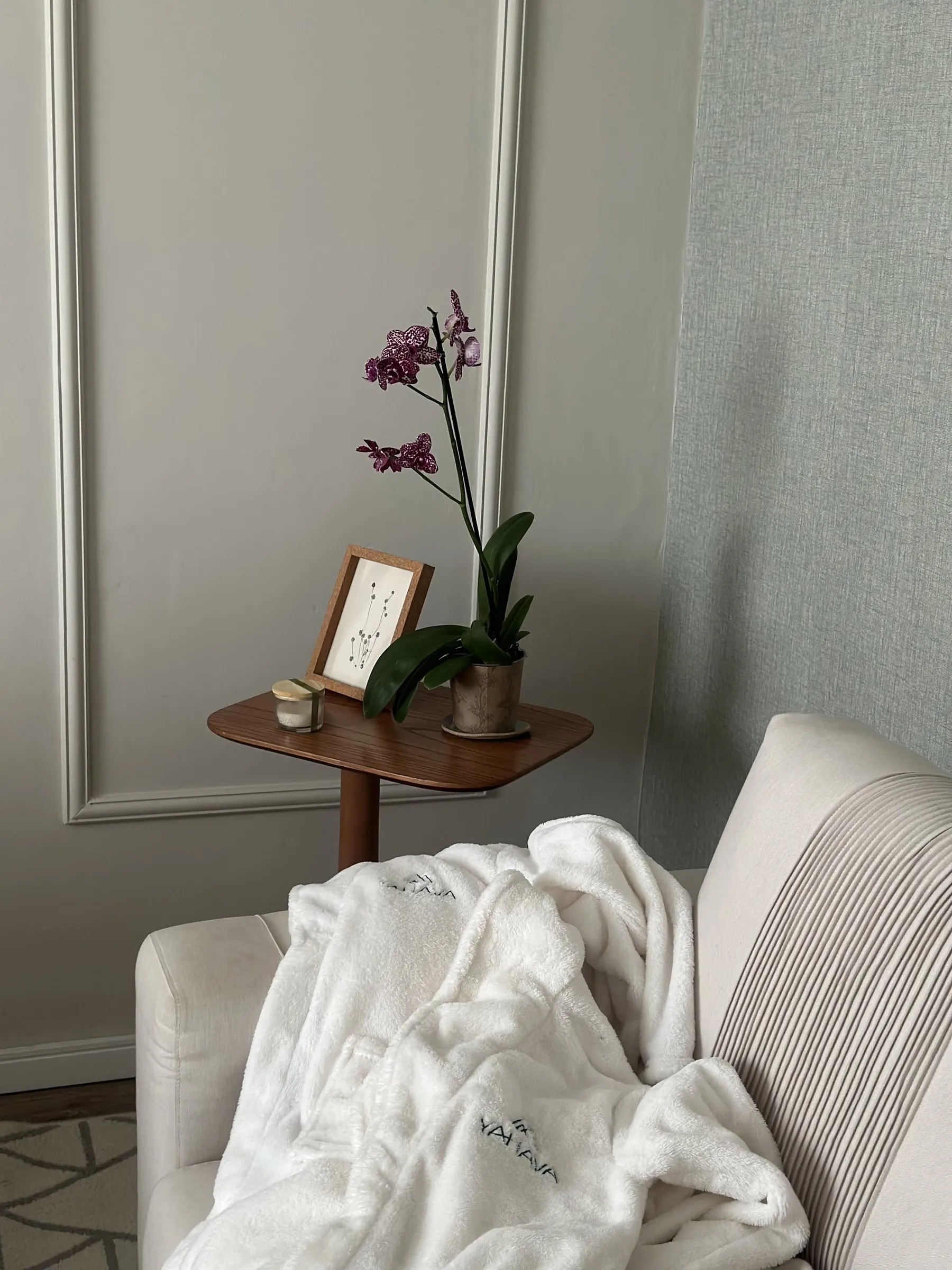 Canto de descanso da Casa Yahava, com poltrona, roupão branco com o bordado Yahava e uma orquídea