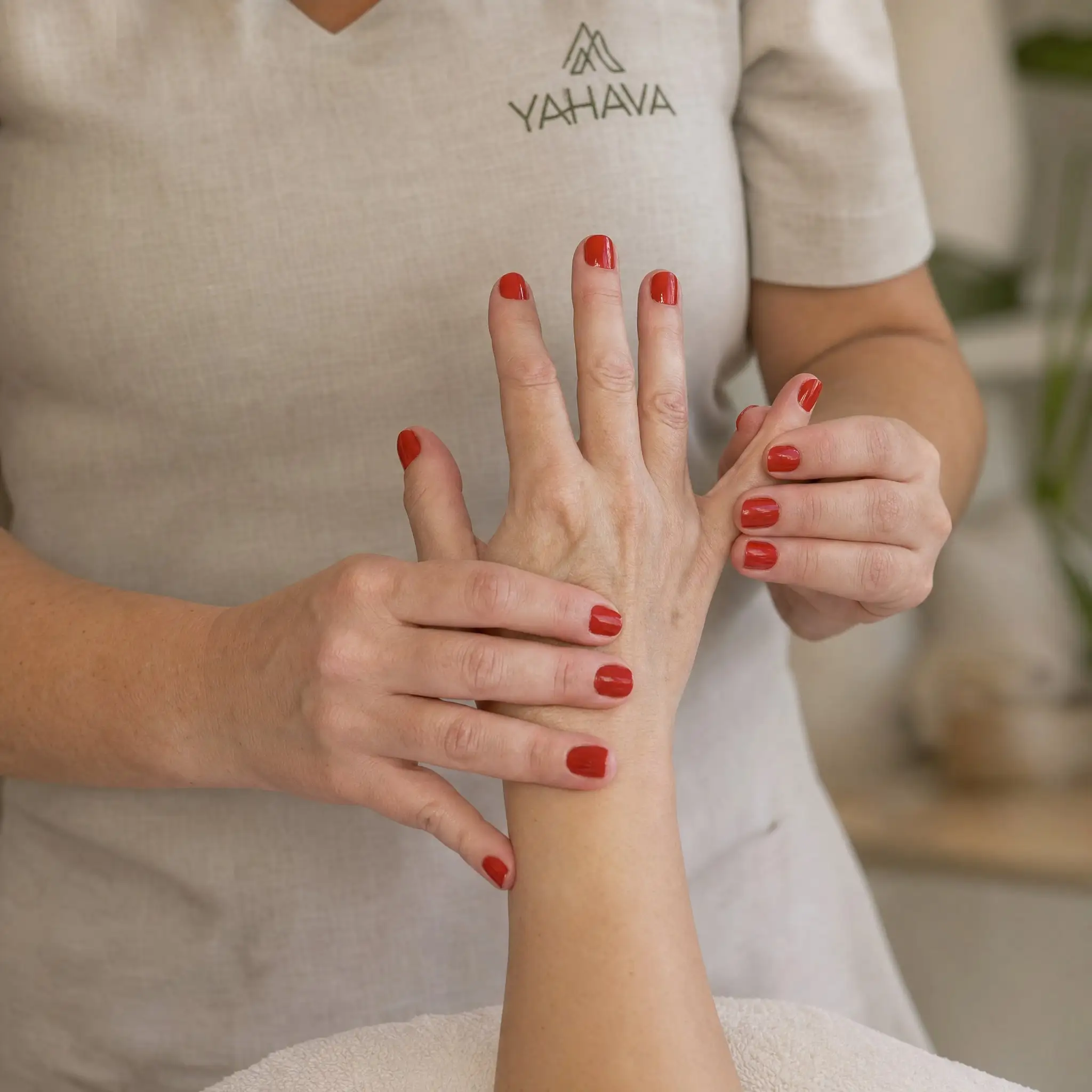 Terapeuta da Yahava, de uniforme, massageando a mão e o antebraço de uma cliente