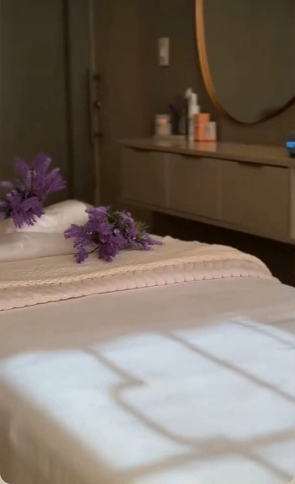 Maca coberta de linho, com ramos de lavanda e a luz da janela desenhando uma grade sobre o lençol, numa sala da Casa Yahava